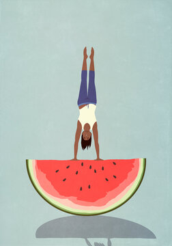 Happy, healthy woman doing handstand on top of watermelon slice
