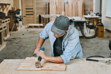 Carpenter works with wood in carpentry workshop. Man doing woodwork professionally