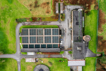Fototapeta na wymiar Aerial top down view on a small factory building and fresh green grass field around it. Clean ecology production concept. Keeping earth clean while producing products for mass production