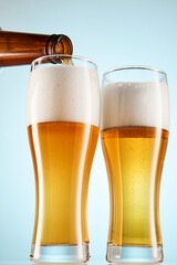 Beer is pouring from amber bottle mockup to glasses.