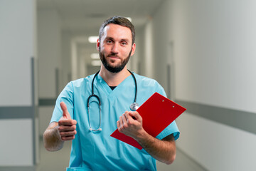 Portrait of a smiling doctor with a beard and a stethoscope on his neck holds folder with documents and shows class to the camera