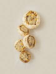 Top quality stuffed mushrooms cups on a cooking paper. High quality product with breadcrumbs, cheese and herbs for baking in oven.