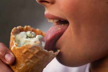 Teenage boy eating snacks close-up. Snack, sweets, street food. Intermediate meal. Mouth with teeth, tongue and saliva - obrazy, fototapety, plakaty