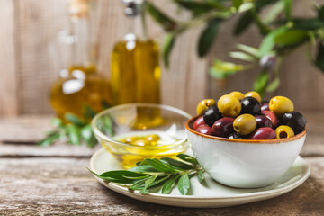 Green, black and red olives, olive oil on a brown wooden background. Fresh juicy olives in a bowl...