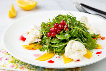 arugula salad with peach slices and red berries on a white plate top view