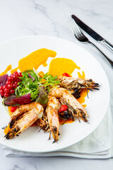  cooked shrimp with herbs and berries on a white plate, side view