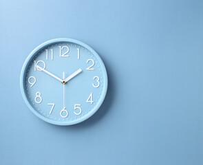 wall clock on blue paper background with copy space
