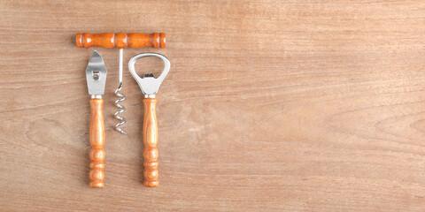 bar set (bottle opener, wine opener, can opener) on wood background with copy space