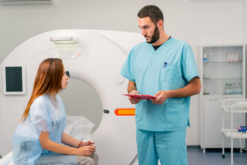 A radiologist consults a girl patient before undergoing diagnostics using an MRI machine in medical...