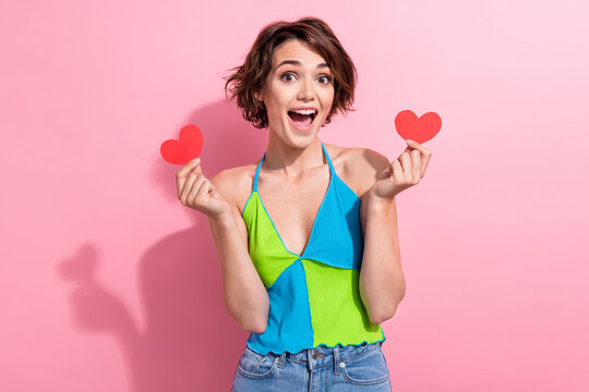 Photo of cheerful excited lady wear green blue tank top open mouth rising two red hearts isolated pink color background