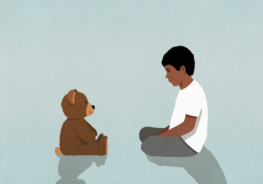 Boy sitting and staring at teddy bear

