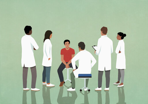 Doctors and residents studying, listening to patient in hospital
