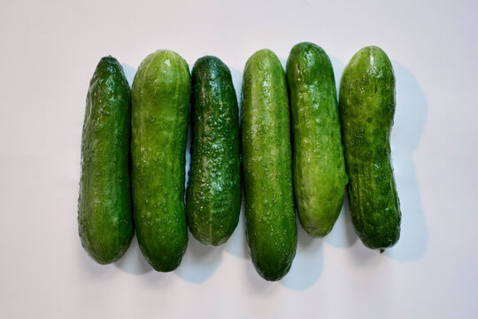 View from above still life fresh green cucumbers in a row on white background
