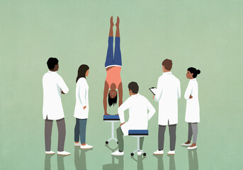 Doctors and medical interns observing energetic woman doing handstand
