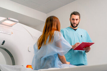 Close-up shot of a radiologist carefully recording the patient's complaints and symptoms before examining her on computed tomography scan - obrazy, fototapety, plakaty