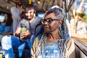 Mulher senior com pentedo afro, sentado no onibus lotado.