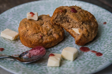 Bitten raspberry white chocolate chip cookies on a plate on top of wooden rustic background
