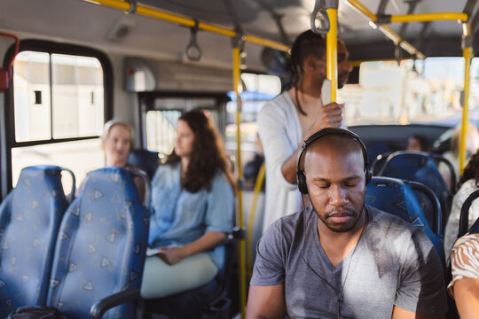Homem usando fones de ouvido ouvindo musica em viagem de onibus.