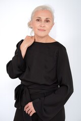 Aged mature woman in black suit on white background with smooth healthy skin face. Beautiful aging mature woman with blonde hair and happy smiling touching face. 