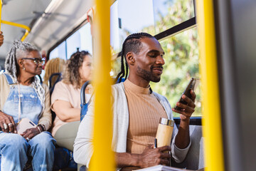 Young black man using smartphone during a bus ride. - obrazy, fototapety, plakaty