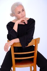 Aged mature woman in black suit on white background with smooth healthy skin face. Beautiful aging mature woman with blonde hair and happy smiling touching face. 