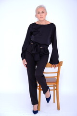 Aged mature woman in black suit on white background with smooth healthy skin face. Beautiful aging mature woman with blonde hair and happy smiling touching face. 