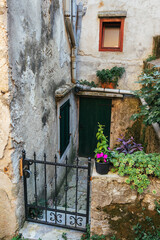 Fototapeta na wymiar The entrance to a small old cramped courtyard with old stone walls and potted flowers