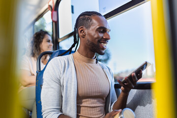 Jovem negro usando smartphone durante uma viagem de onibus.