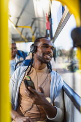 Smiling black man, wearing headphones, listening to music on his smartphone.