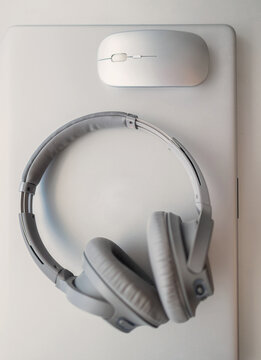 Silver headphones and wireless mouse on laptop