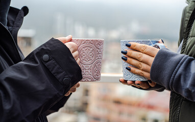 Unrecognizable friends drinking hot tea and coffee in autumnal city outdoors