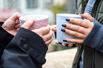 Unrecognizable friends drinking hot tea and coffee in autumnal city outdoor