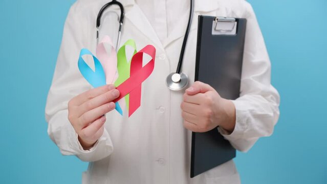 Close up of young woman doctor holding small colorful ribbons, blue, red, green, pink for supporting people living and illness. Health, Medical, awareness and Insurance concept. World cancer day