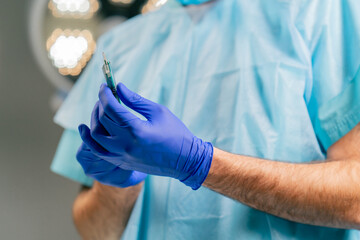 Close-up shot of a surgeon's hands in medical gloves holding scalpel and preparing to open it...