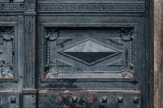 Old matte forged black metal door with stripes and rivets in Lvov, Ukraine. Vintage background closeup.