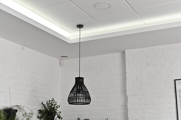 A beautiful lamp on a long wire hangs on the ceiling. against a white wall.