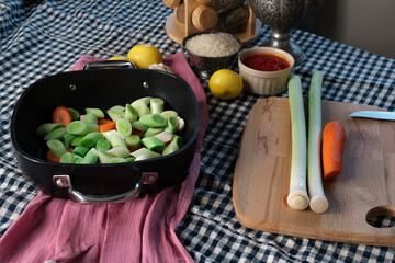 turkish-style braised leeks food cooken in olive oil, fresh vegetables cut process with all ingredients on kitchen textile background, authentic look