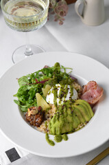 Healthy Breakfast Bowl with Oatmeal, Poached Egg, Salad and Avocado