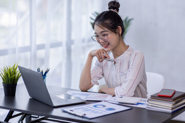 Young Asian Business woman Using laptop computer and working at office with calculator document on desk, doing planning analyzing financial report, business plan investment, finance analysis concept.