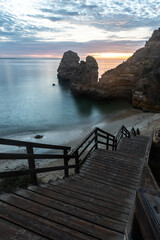 Fototapeta premium Wooden footbridge to beautiful beach Praia do Camilo near Lagos in Portugal at sunrise