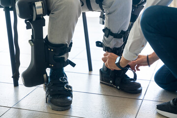 Mechanical exoskeleton, physiotherapist placing the tapes on the legs of the disabled person to...