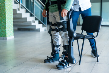 Mechanical exoskeleton, physiotherapist helped disabled person get up with robotic skeleton,...