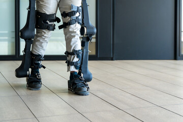Mechanical exoskeleton, unrecognizable disabled person walking with the help of robotic skeleton, physiotherapy in a modern hospital, futuristic physiotherapy