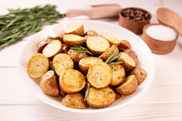 Delicious baked potatoes with rosemary on a light background