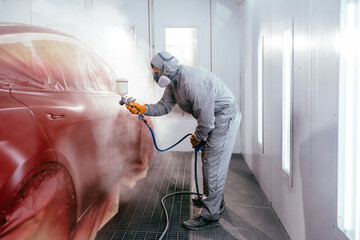 Automotive paint services, quality auto body shop concept. Repairman painter in chamber painting...