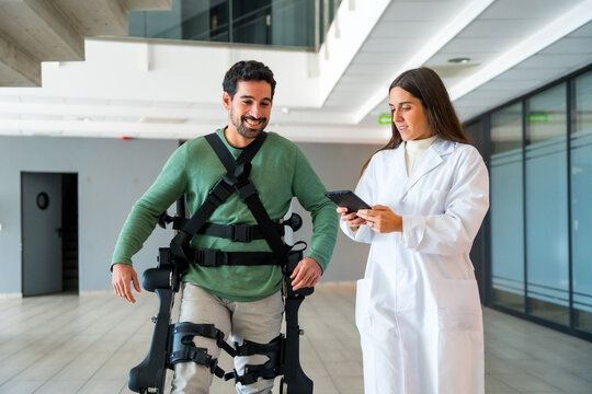 Mechanical exoskeleton, female doctor physiotherapist with disabled person with robotic skeleton in rehabilitation, physiotherapy in a modern hospital, futuristic physiotherapy
