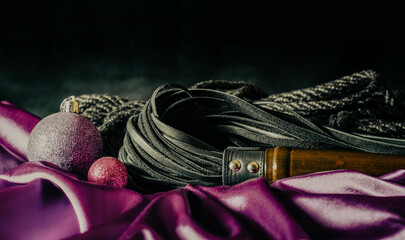 bdsm still life leather whip rope shibari and christmas ball on pink cloth - obrazy, fototapety, plakaty