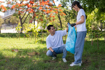 Fototapeta premium Happy young Asian students diverse volunteers with garbage bags cleaning area in the park, The concept of environmental conservation on world environment day, recycling, charity for sustainability.