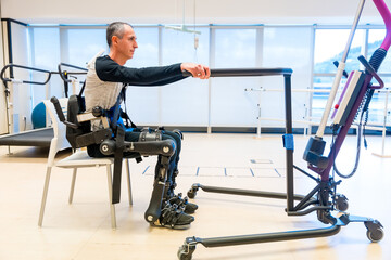 Obraz premium Mechanical exoskeleton. Disabled person with robotic skeleton in rehabilitation trying to get up alone, Physiotherapy in a modern hospital