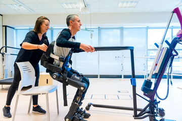 Mechanical exoskeleton. Physiotherapy medical assistant lifting disabled person with robotic...